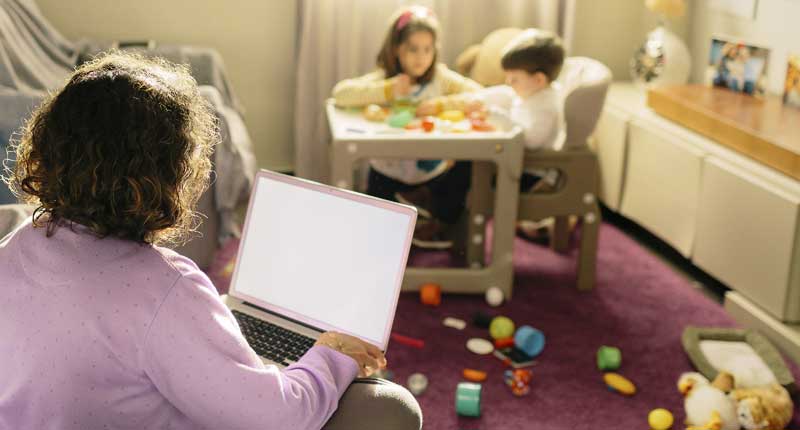 Woman working from home with children playing in background