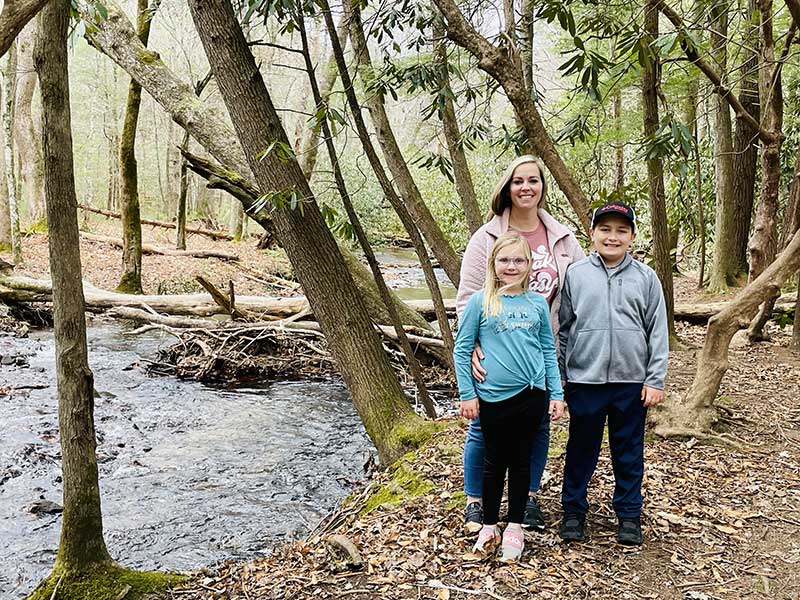 Leslie enjoying time with her children in the woods by a stream