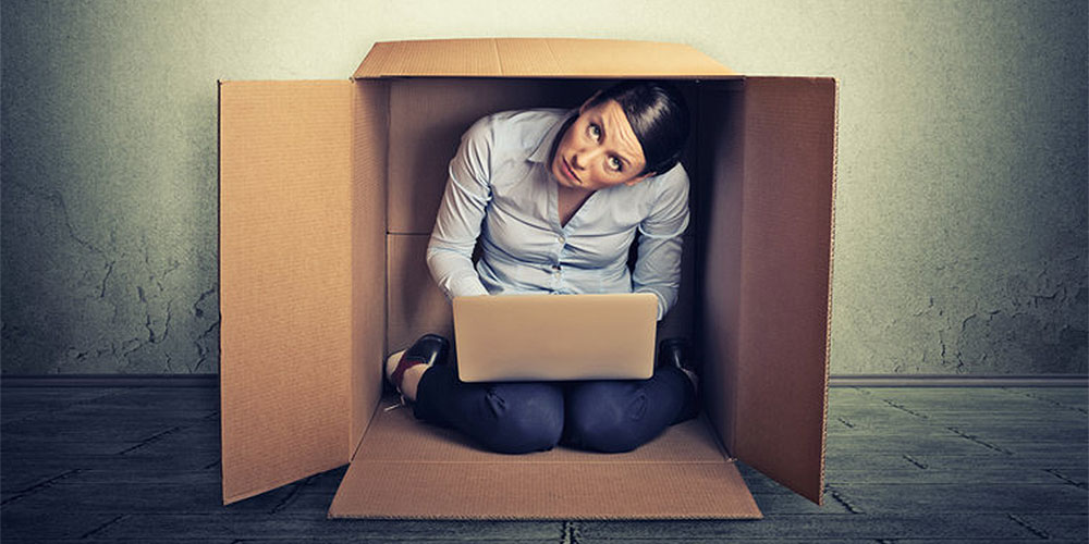 Woman entrepreneur sitting inside a cardboard box working on her laptop