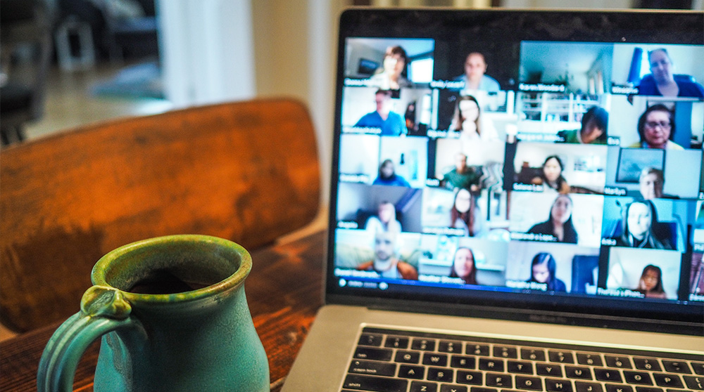 Laptop and coffee mug on desk with Zoom session ongoing